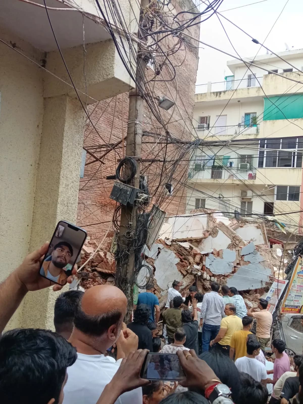Rescue workers and crowds gathered around the completely collapsed Daze PG building in Delhi's Satya Niketan area.